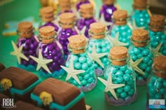 there are many small bottles filled with candy and starfish decorations on top of the table