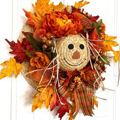 a scarecrow wreath with autumn leaves and pumpkins