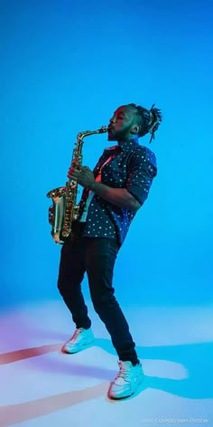 a man with dreadlocks playing a saxophone in front of a blue background,