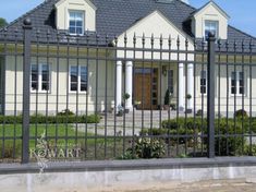 a white house behind a black fence