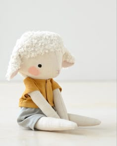 a small stuffed sheep sitting on top of a white floor