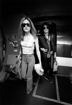 black and white photograph of two women walking in an airport terminal, one with sunglasses on her head