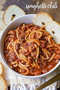 a bowl filled with spaghetti and bread on top of a table