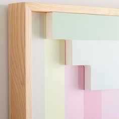 a wooden frame with pastel colors on the wall behind it and a white background