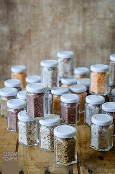 many jars filled with different kinds of food on top of a wooden table next to each other