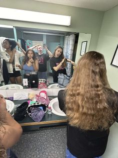 a group of women standing in front of a bathroom mirror