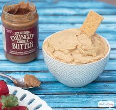 a bowl of peanut butter next to a plate of strawberries