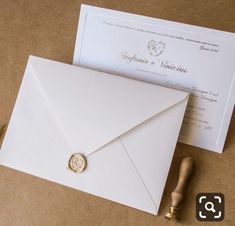 a white envelope with a wax stamp on it next to a piece of paper and a pen