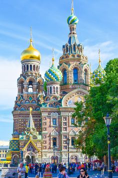 people walking around in front of an ornate building with gold and blue domes on it