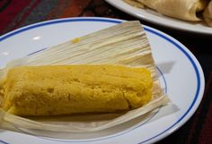 two plates with food on them and one plate has rice wrapped in banana leaf wrappers