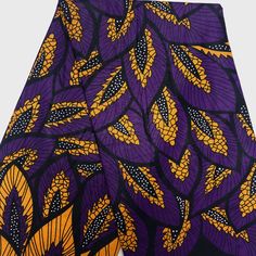 an african print fabric with yellow and purple leaves on it's side, showing the pattern