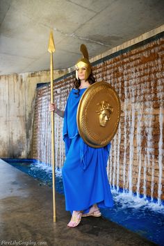 a woman dressed in blue holding a golden shield and spear