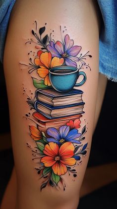 a woman's thigh with books and flowers on it, as well as a tea cup