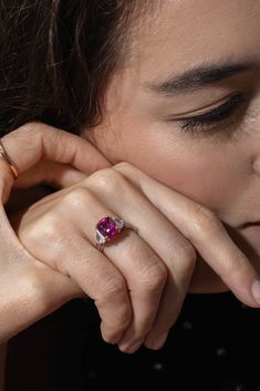 a close up of a person wearing a ring with a pink stone in the middle