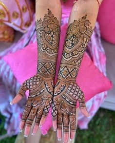 two hands with henna tattoos on them, one is showing off the intricate design