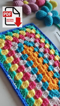 a crocheted square is sitting on a table next to some knitting needles and yarn