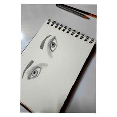 a notebook with an eye drawn on it next to a pencil and eraser pen