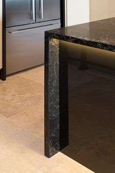 a kitchen with marble counter tops and stainless steel refrigerator freezer in the back ground