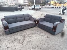 two gray couches sitting on top of a dirt field next to a motor scooter