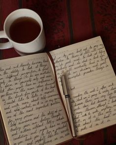 an open notebook with writing on it next to a cup of tea