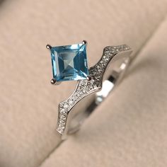 an engagement ring with a blue topazte and diamond accents on the side, sitting in a box