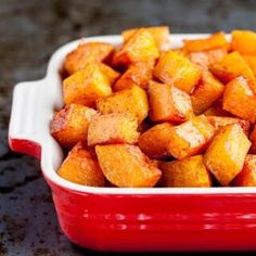 a red casserole dish filled with cubed sweet potatoes