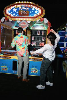 two people standing in front of a carnival machine