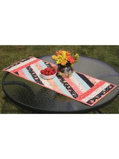 a table with a bowl of fruit on it and flowers in a vase sitting on top