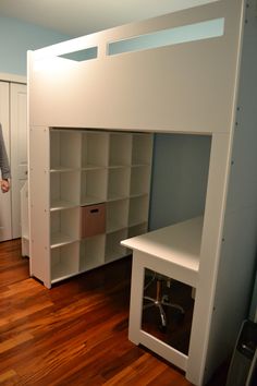 a white loft bed with built in desk and shelves