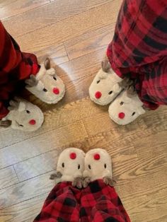 three people wearing slippers with red noses and nose shapes on their feet, standing in the middle of a wood floor