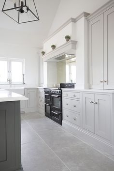 a large kitchen with white cabinets and black stove top oven in the center, along with an island