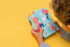 a young boy reading a children's book on a yellow background with his hands