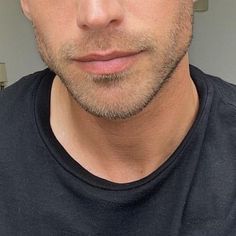 a close up of a man wearing a black t - shirt looking at the camera