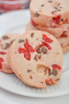 three cookies with chocolate chips and strawberry jam are on a white plate, ready to be eaten