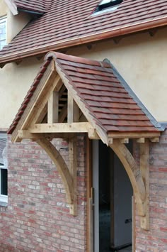 a wooden arch in front of a brick building with an open door and brown tiled roof