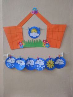 a paper house with clouds and sun hanging from it's side next to clothes pins