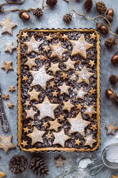 a cookie tart topped with chocolate and star shaped cookies next to other christmas decorations