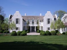 a large white house surrounded by trees and grass