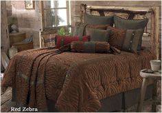 a bed covered in brown and red comforter next to a wooden headboard with a mirror above it