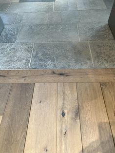 the floor is made out of wood and has gray tiles on it, along with a black door