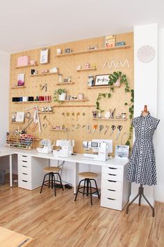 a sewing studio with lots of crafting supplies on the wall and desks in front of it