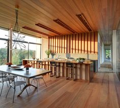 an open kitchen and dining room with wood flooring, large windows, and wooden ceiling