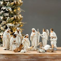 a group of figurines sitting on top of a table next to a christmas tree