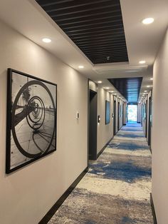 an empty hallway with pictures hanging on the wall and carpeted flooring in front of it