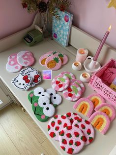 a table topped with lots of knitted items on top of a wooden table next to a candle