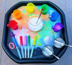 a child's play tray with different colored paints and utensils in it