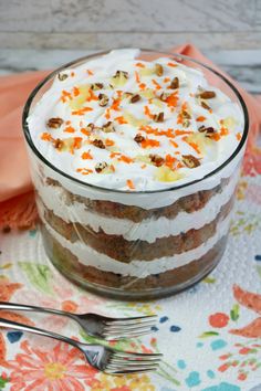 carrot cake in a glass dish with whipped cream on top and chopped carrots around the edges