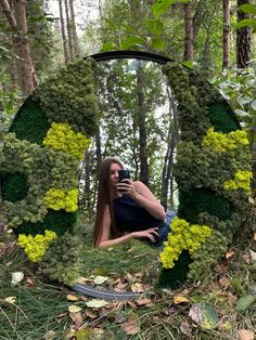 a woman taking a selfie in front of a mirror with moss growing on it