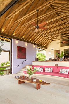 a living room filled with furniture under a wooden roof