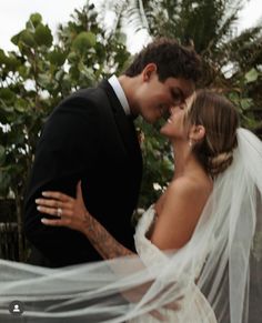 a bride and groom kissing under a veil